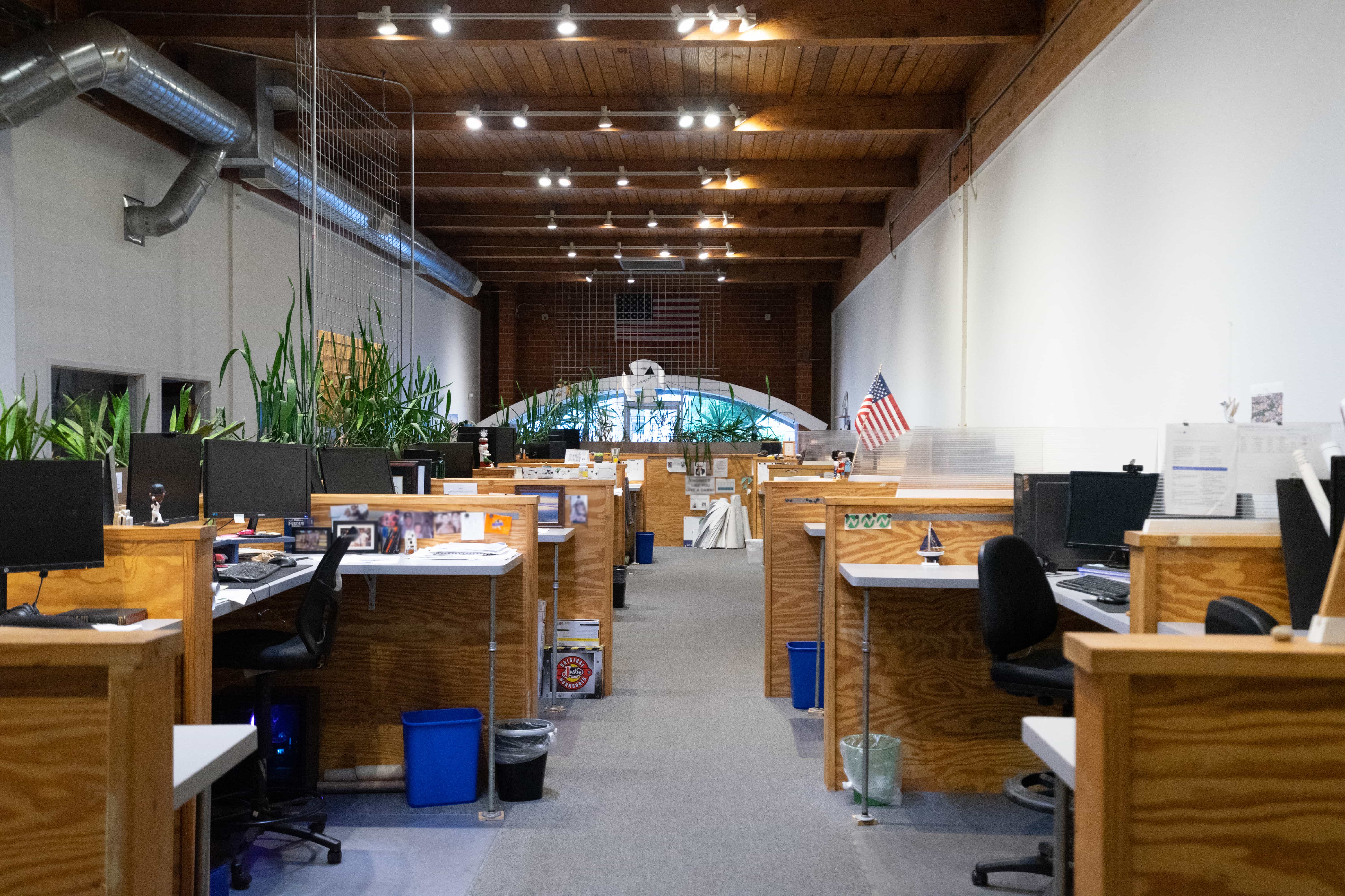 Long open office in Unit 210 with exposed wood beam ceilings, ductwork and workstations