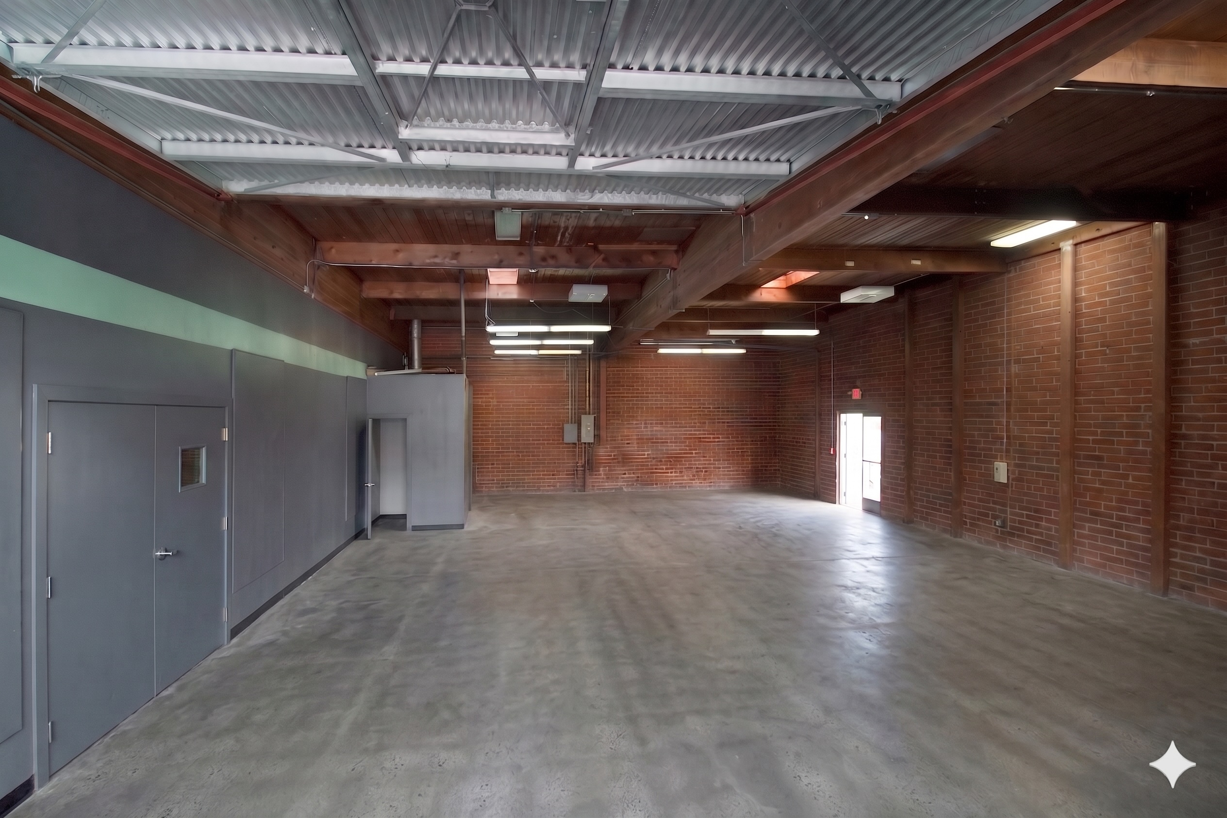 Interior of Unit 218 with exposed beams, brick wall and concrete floor