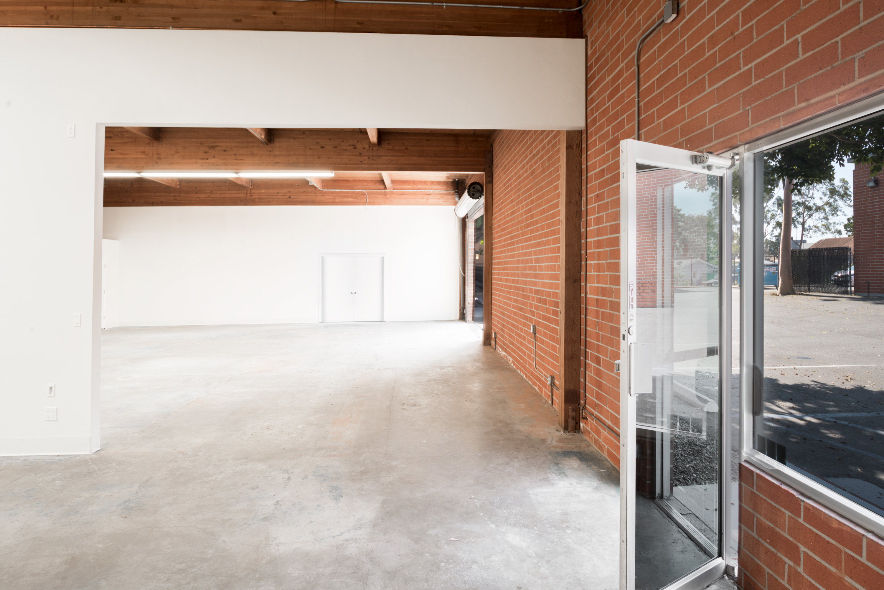 Unit 220 open floor with brick wall and glass entry door